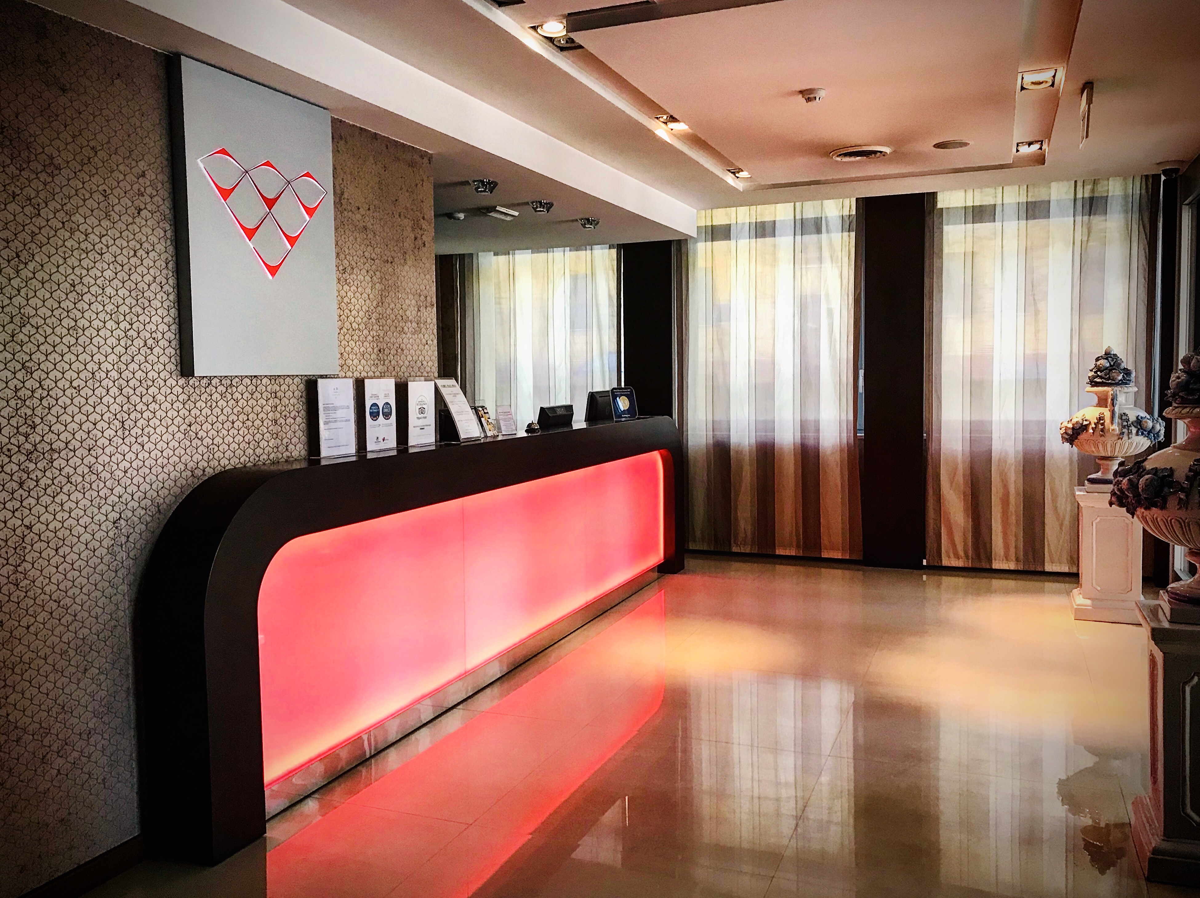 Area reception di un palazzo con illuminazione calda e arredi pratici, in un contesto sobrio e accogliente.