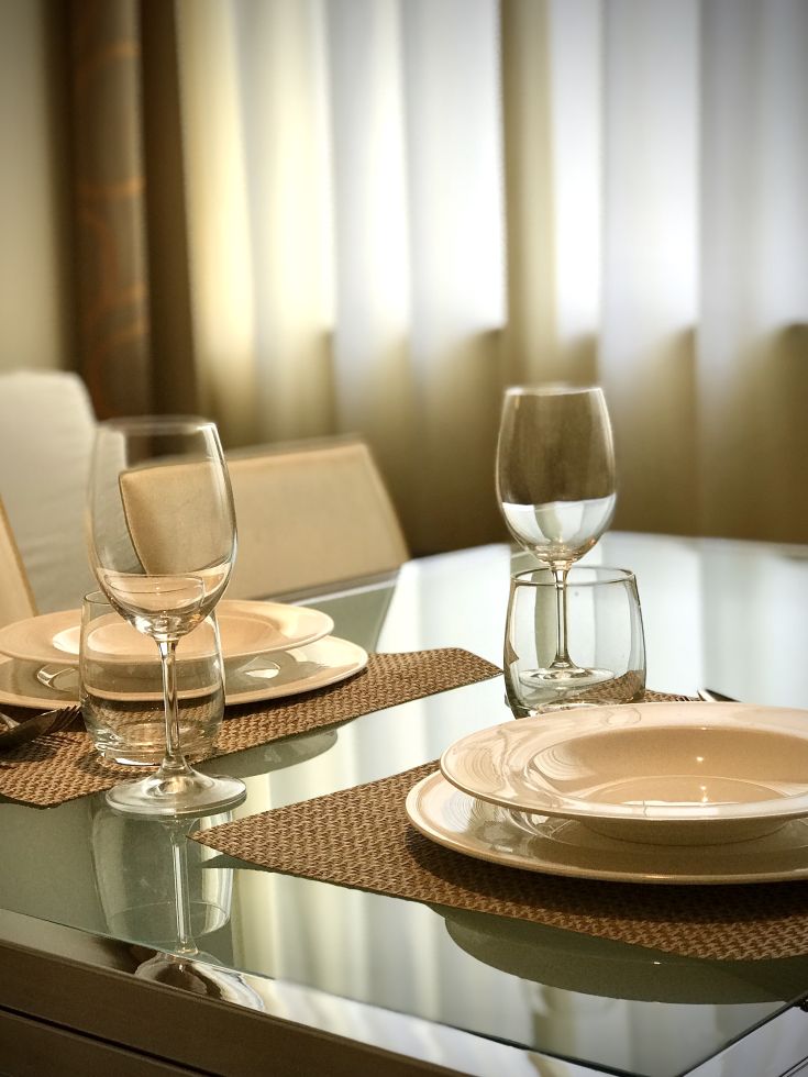 Une table joliment dressée avec des assiettes et des verres dans une ambiance claire et accueillante.