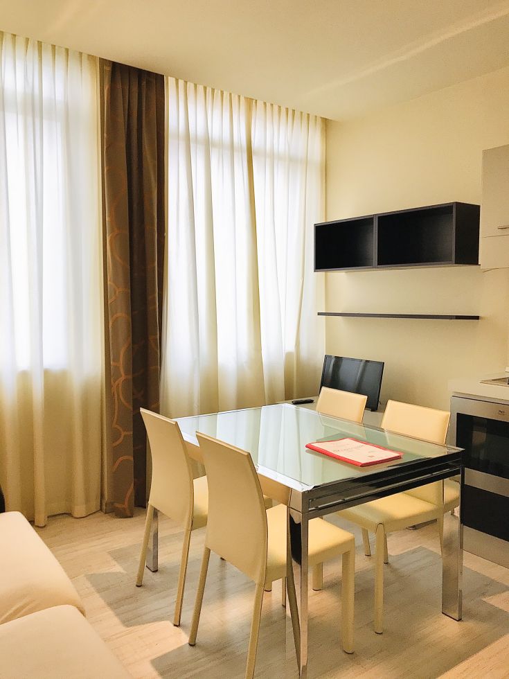 Intérieurs lumineux et linéaires du palais, avec une table en verre et des chaises au design simple.