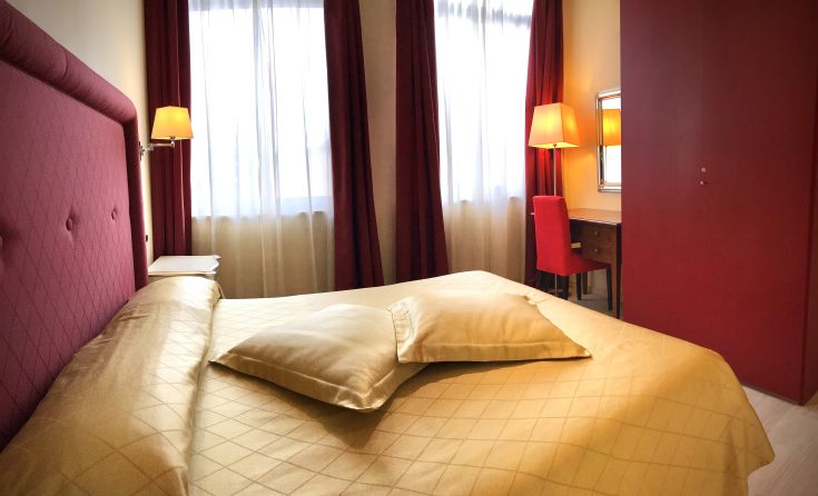 Chambre simple avec un lit double et un mobilier minimal, décorée avec des éléments essentiels.