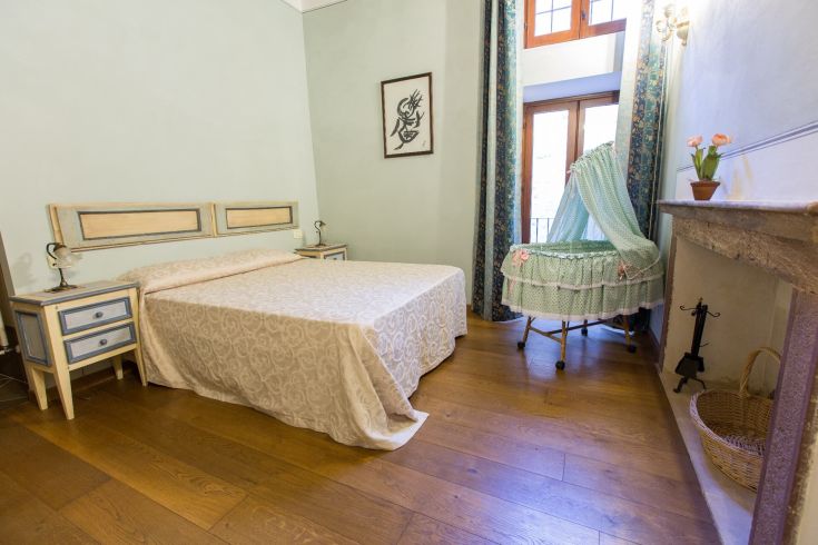 Camera ospitale con letto matrimoniale e culla, ben illuminata e circondata da spazi verdi.