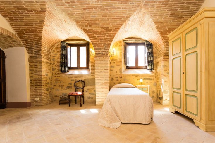 Camera dal soffitto a volta posta in un tranquillo borgo medievale, ideale per un soggiorno rilassante.