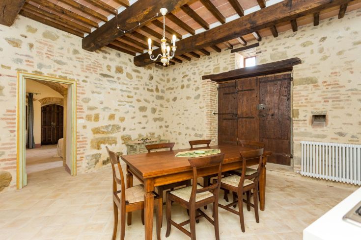 Interno di un palazzo con un tavolo in legno e soffitti con travi a vista, ideale per momenti conviviali.