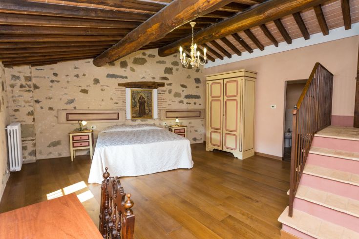 Camera semplice con pareti in pietra e mobili tradizionali, adatta per un soggiorno tranquillo.