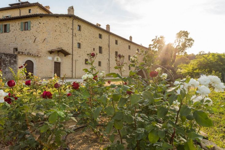 Particolare del Borgo Colognola, immerso nella vegetazione con rose, che circondano un antico edificio.