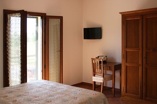 Einfaches Zimmer mit Doppelbett, Tisch und Blick auf die umliegende Landschaft.