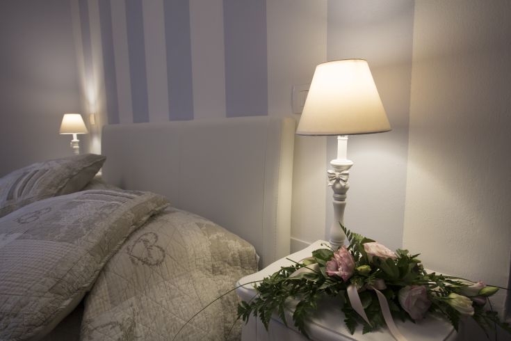 A simple and cozy bedroom design with a lamp and decorative plants.