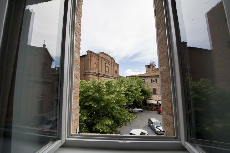 View from a window showcasing Città della Pieve with ancient buildings and green trees.