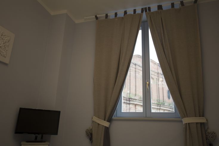A cozy room interior with curtains facing a historical building.