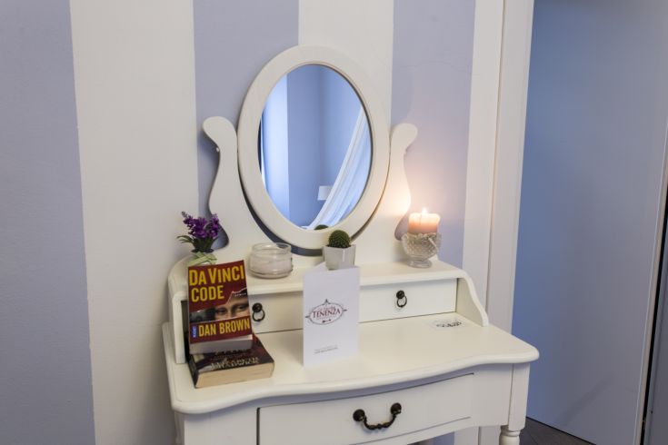 A shabby chic mirror setting with arranged books and a lit candle on the table.