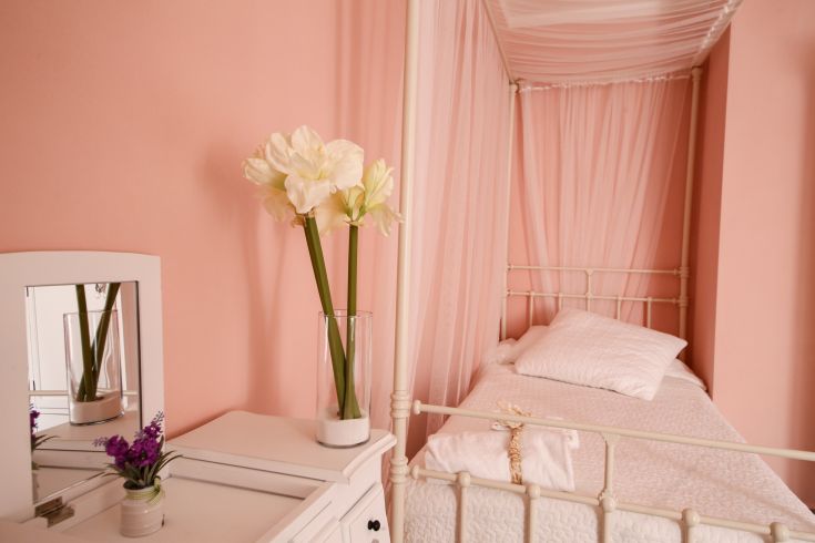Cozy room featuring simple design with pink tones and floral decorations.