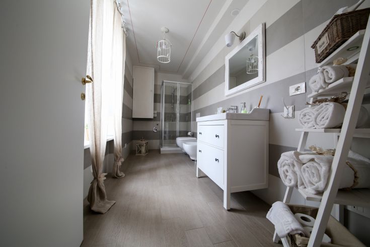 Elegant bathroom with light tones and shabby chic decor, well-lit space.