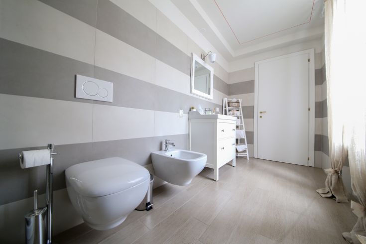 A sleek bathroom featuring light striped walls and functional décor.