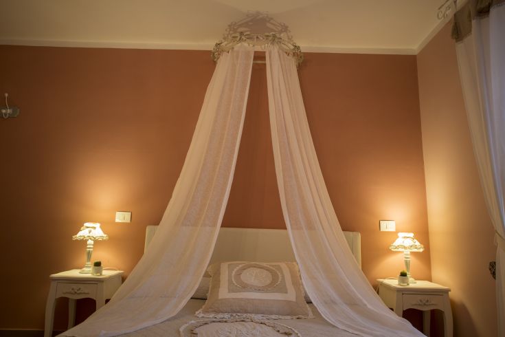A room with a double bed, white sheets, and soft lamps, perfect for a peaceful stay.