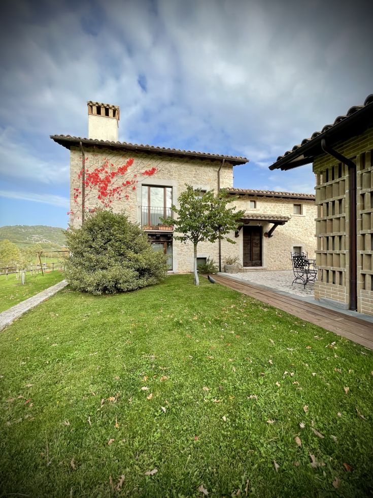 Un edificio circondato da vegetazione, con dettagli architettonici discreti e paesaggio naturale.