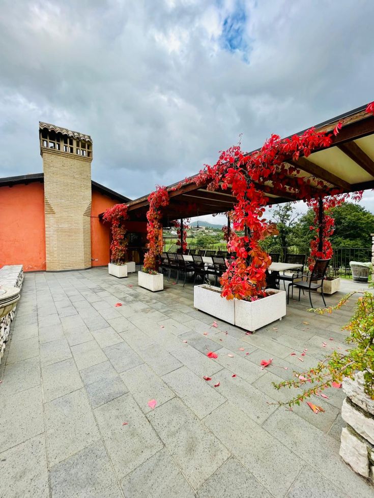 Una terrazza con piante rampicanti e foglie di un intenso colore rosso autunnale.