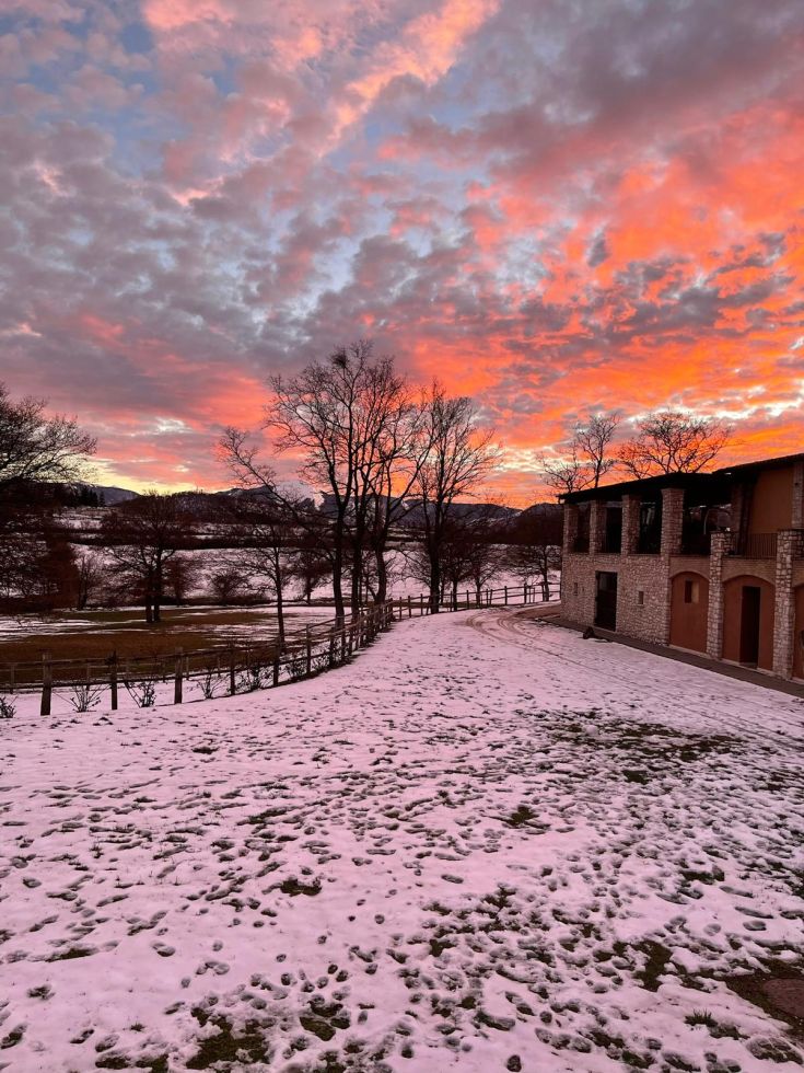 Un tramonto invernale colora il cielo su un paesaggio ricoperto di neve.