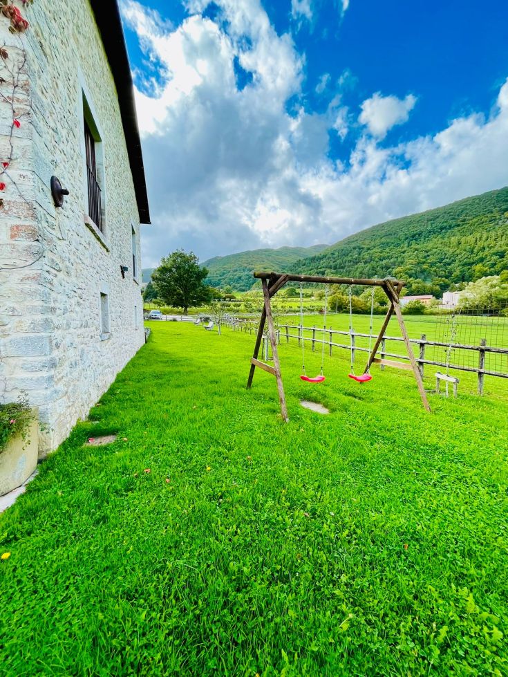 Un'area verde con un'altalena rossa, immersa in un ambiente naturale e tranquillo.
