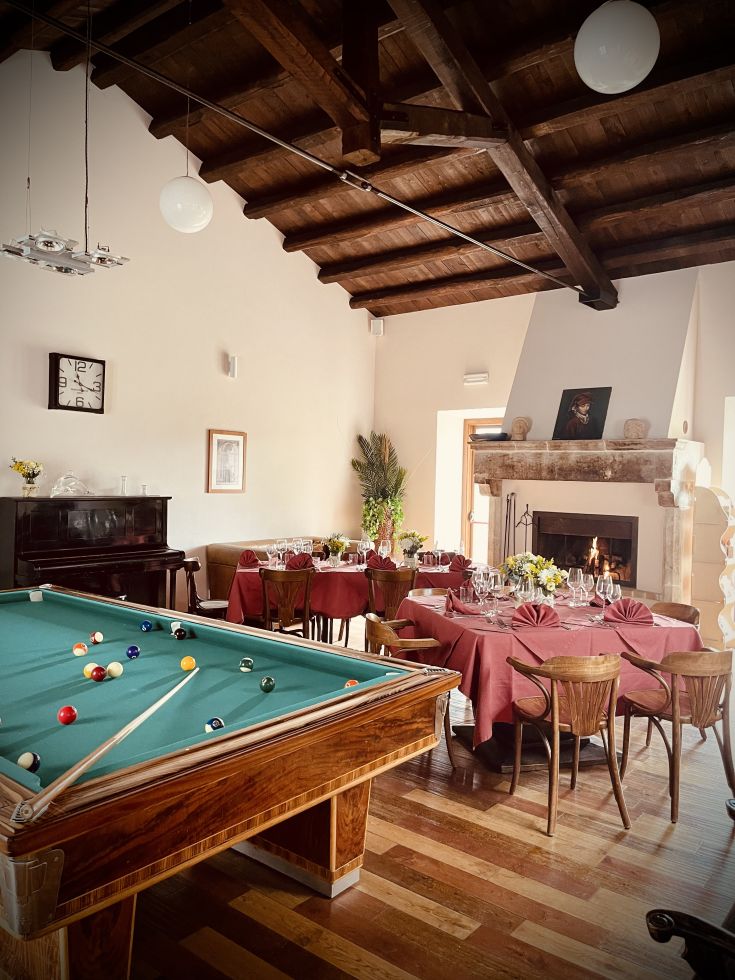 Un ambiente spazioso con un tavolo da biliardo e tavoli apparecchiati per una cena raffinata.