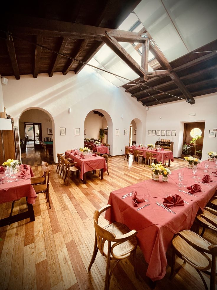 Un ambiente confortevole, con tavoli apparecchiati e semplici decorazioni floreali.