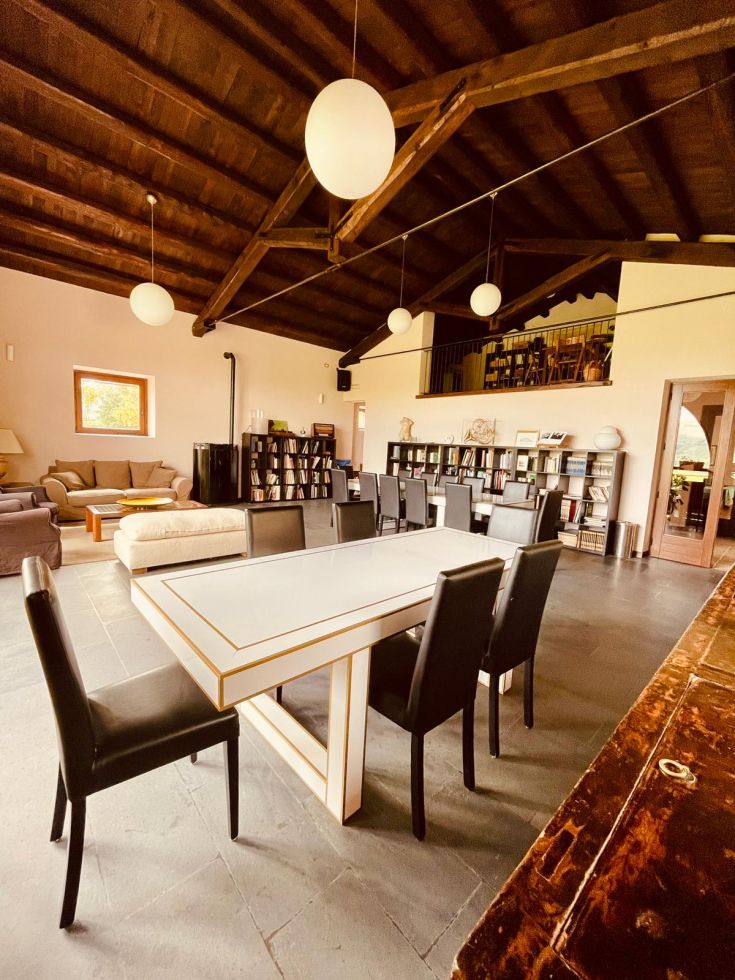 Un soggiorno spazioso con un tavolo elegante e mobili contemporanei, illuminato da lampade a forma rotonda.