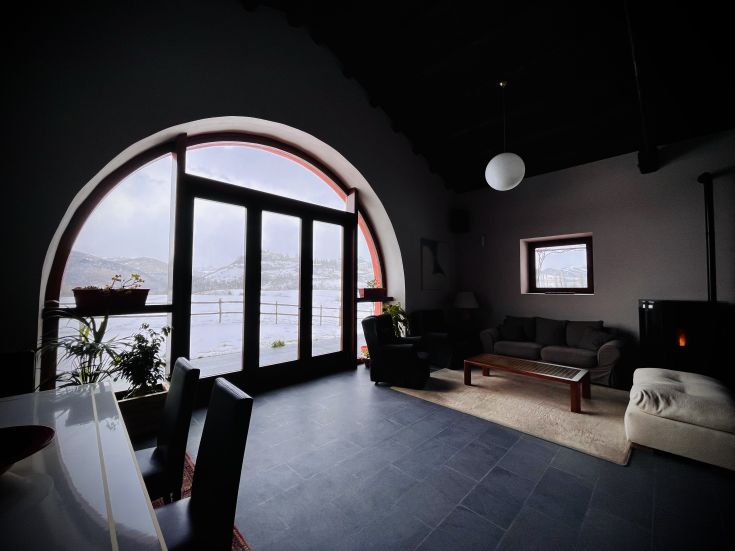 Interno accogliente di un agriturismo con panorama sulle montagne innevate.