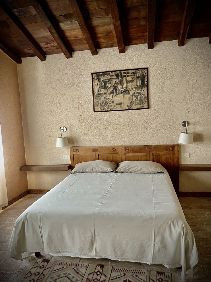 Una camera accogliente con letto matrimoniale e decorazioni semplici sulle pareti.