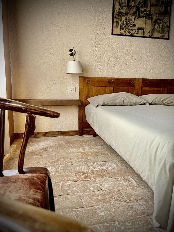 Una camera da letto semplice con un letto matrimoniale e una sedia dal design rustico.