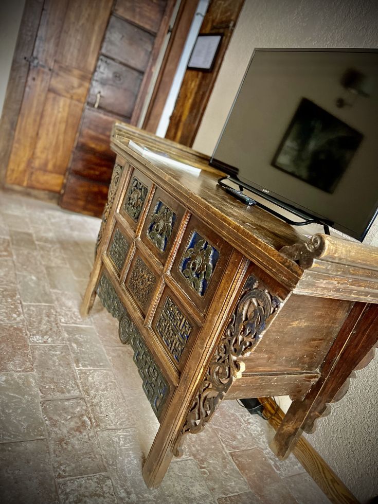 Un mobile in legno chiaro con TV posizionata sopra, collocato in un ambiente accogliente e rustico.