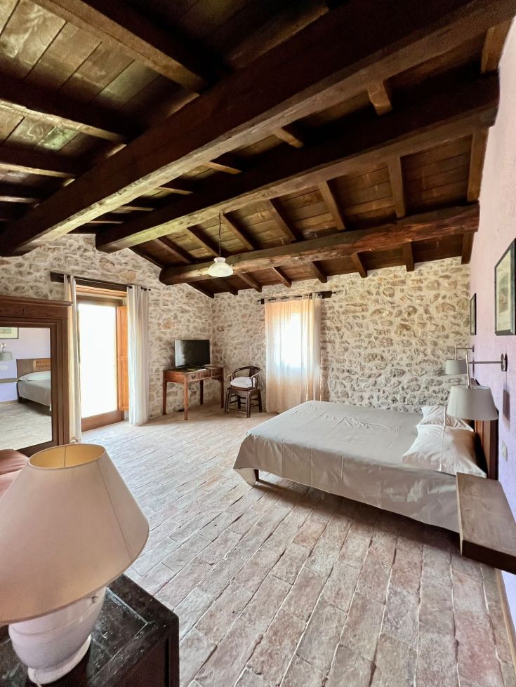 Spazio semplice di un agriturismo, con soffitti in legno e pareti in pietra che creano un'atmosfera rustica.