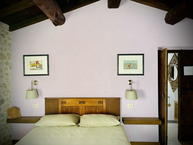 Camera confortevole con pareti lavanda, letto in legno e illuminazione soffusa.