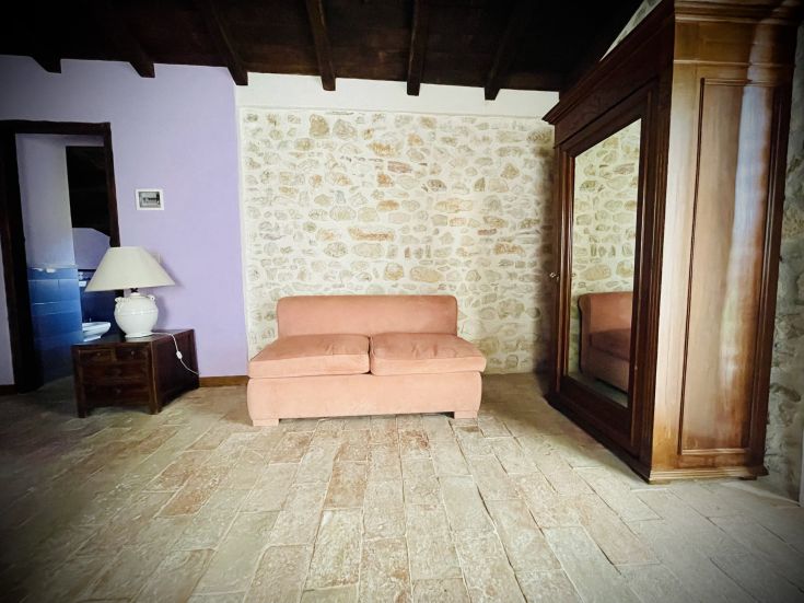 Un soggiorno semplice con un divano, una lampada e un armadio, arredato in modo rustico.