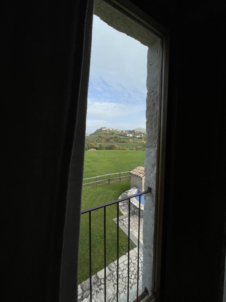 Panorama visibile da una finestra che mostra un paesaggio naturale caratterizzato da alberi e prati verdi.