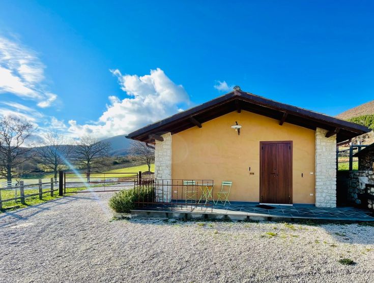 Un semplice edificio di campagna immerso in un paesaggio di prati verdi e cielo sereno.