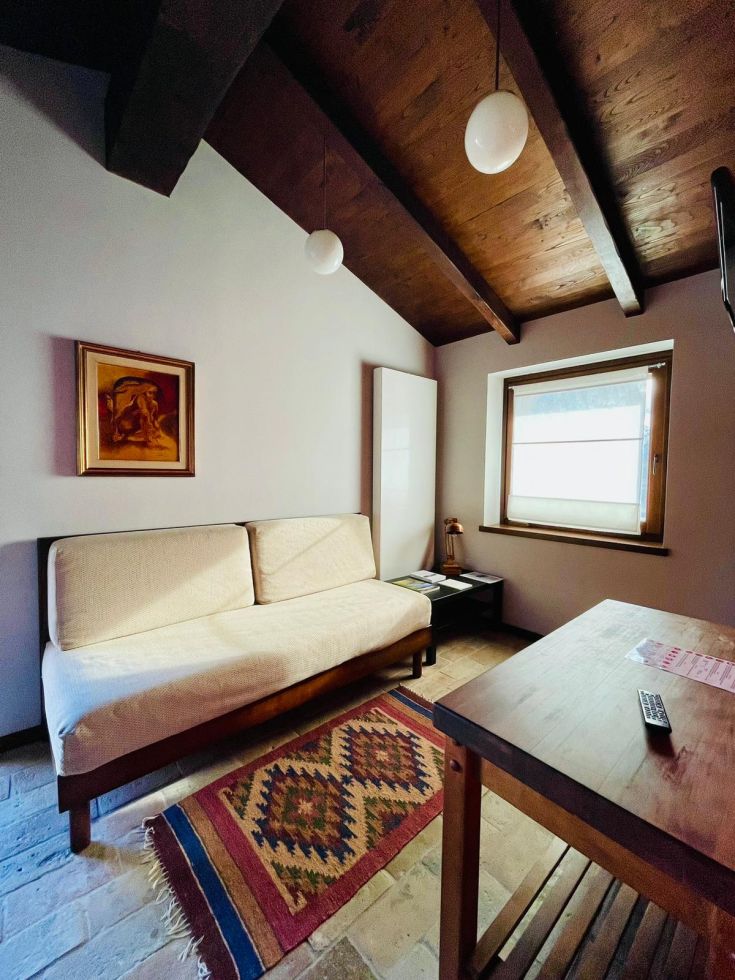 Stanza semplice con divano e decorazioni in stile rustico, adatta per momenti di relax.