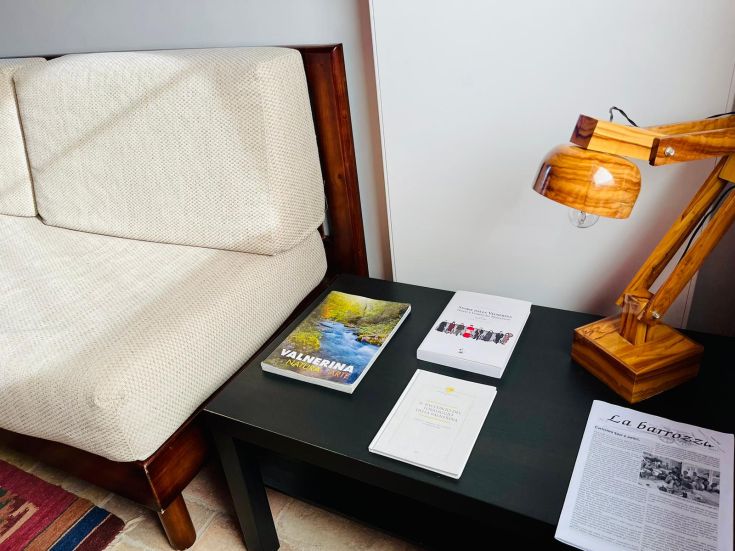 Un'area confortevole con un divano, una lampada in legno e libri disposti su un tavolino.