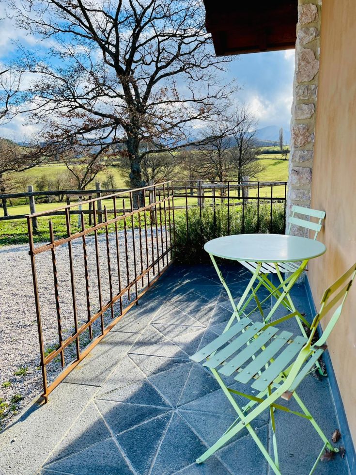 Un'area all'aperto con un tavolo e delle sedie verdi, immersa nella natura circostante.