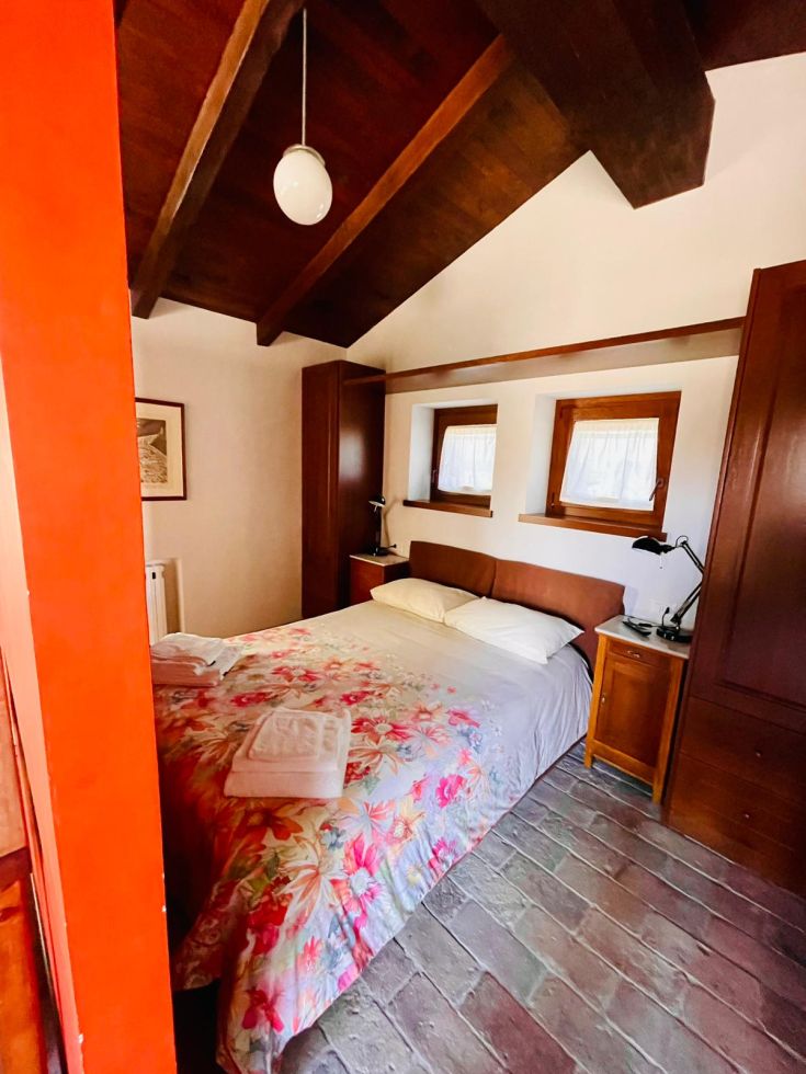 Camera luminosa e semplice con decorazioni floreali e travi di legno a vista.