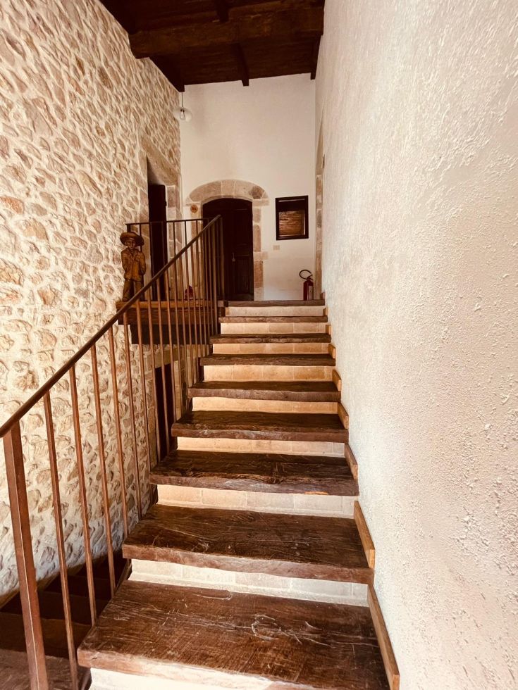 Dettaglio di una scala in legno, con pareti in pietra e decorazioni in stile rustico.