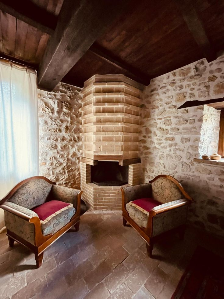 Area confortevole di un agriturismo, dotata di poltrone e un camino in pietra.