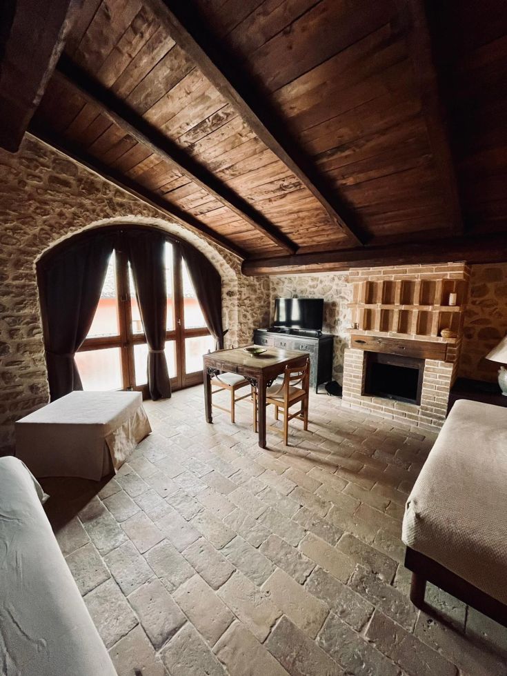 Ambiente interno piacevole con travi in legno a vista e pareti in pietra, arredato in modo funzionale.