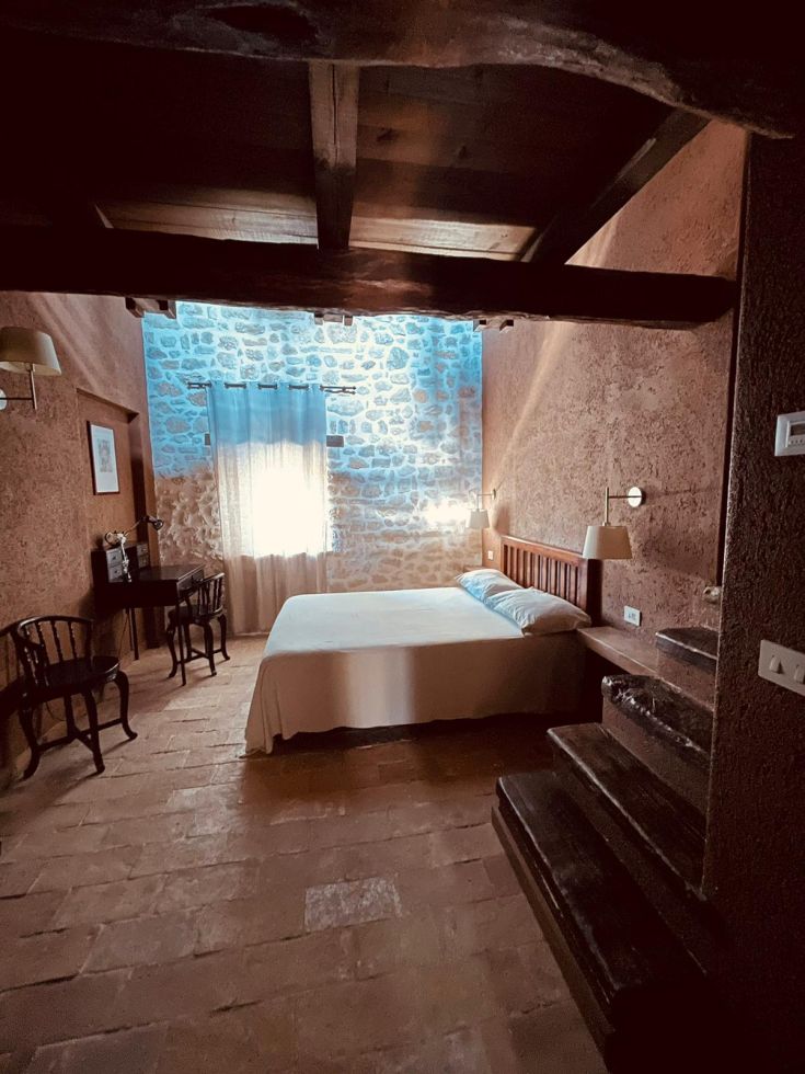 Camera dal design rustico, con pareti in pietra e illuminazione naturale che la rende gradevole.