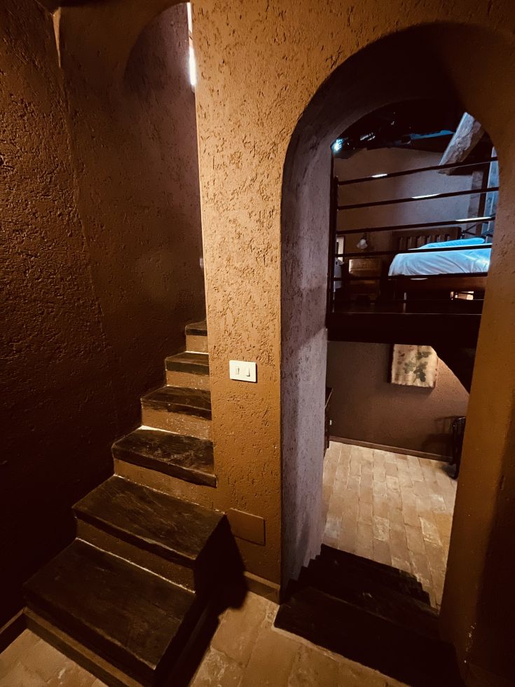 Un angolo semplice con scale in pietra che conducono a una camera da letto, in un ambiente rustico e intimo.