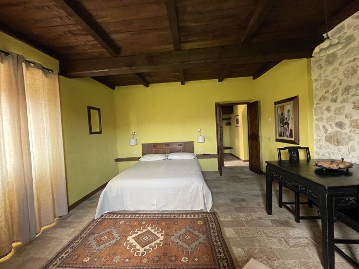 Camera accogliente con dettagli rustici e panorama sul paesaggio verde.