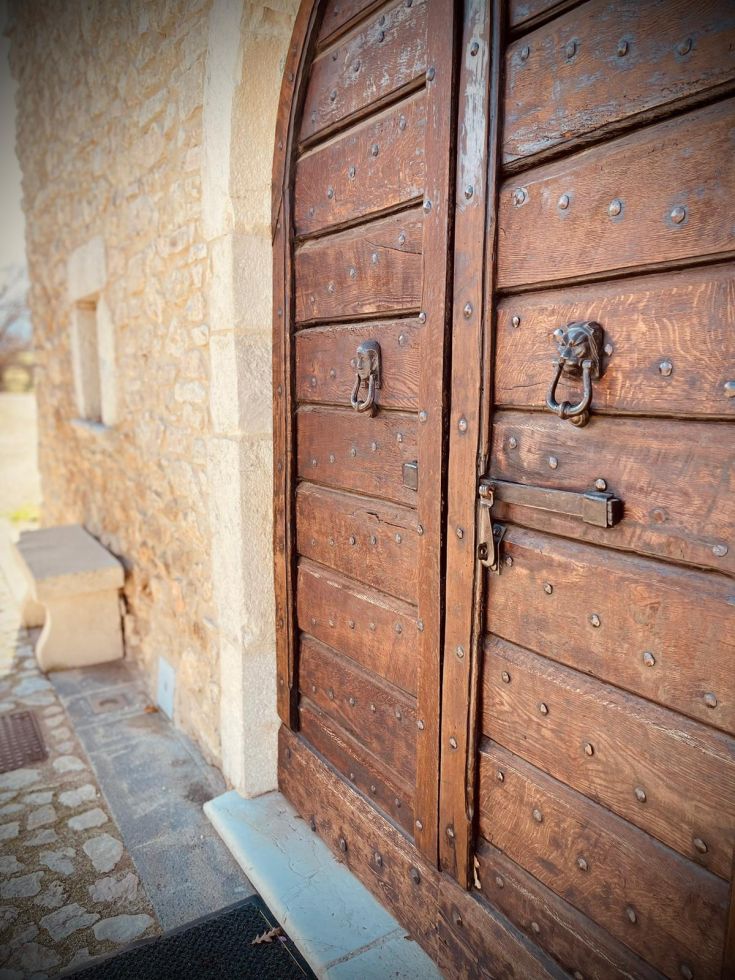 Portone in legno con dettagli artigianali, inserito in una struttura di pietra.