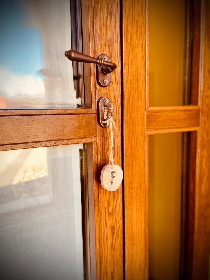 Particolare di una chiusura in legno di una porta, con una chiave appesa a un nastro. Ambientazione sobria.
