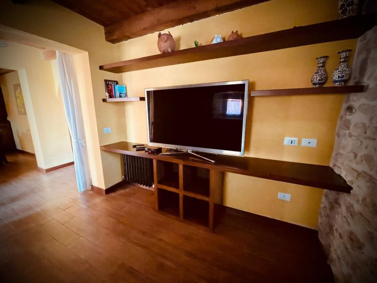 Un soggiorno confortevole con TV e mensole di legno, perfetto per momenti di svago e relax.