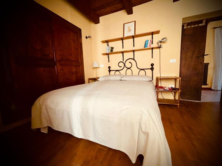 Spazio intimo in stile rustico, dotato di letto matrimoniale e arredamento semplice.
