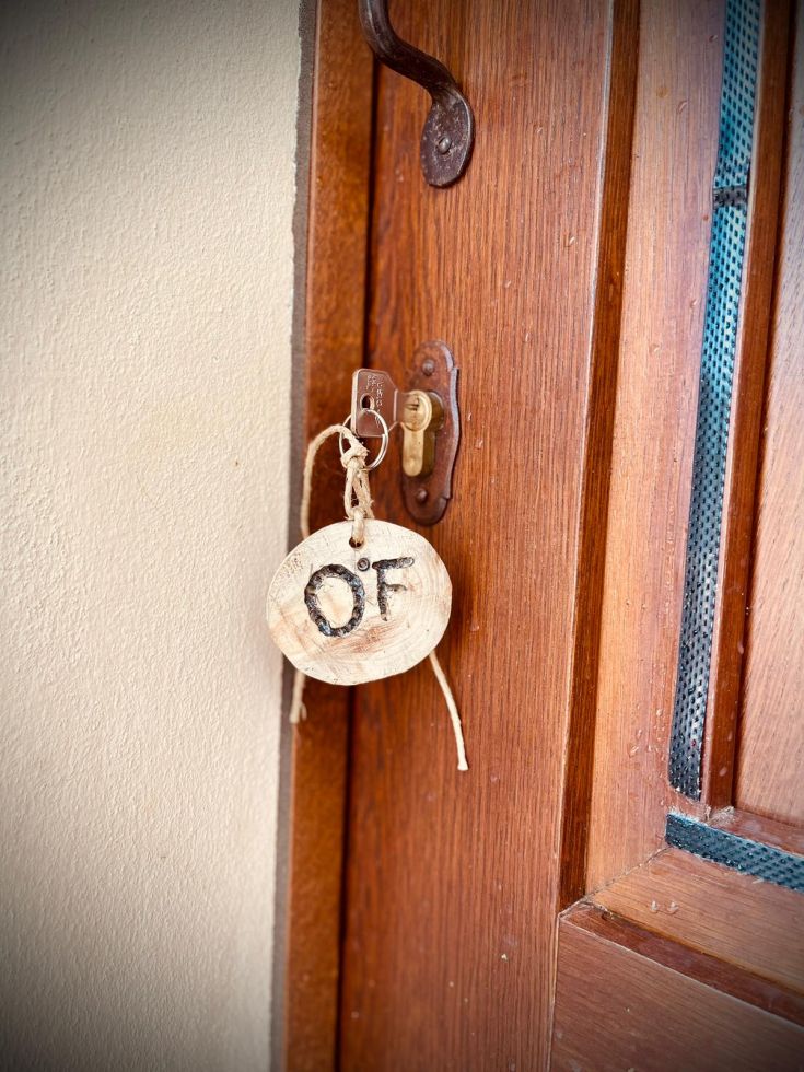 Un portachiavi in legno, semplice e funzionale, sospeso a una porta di legno.