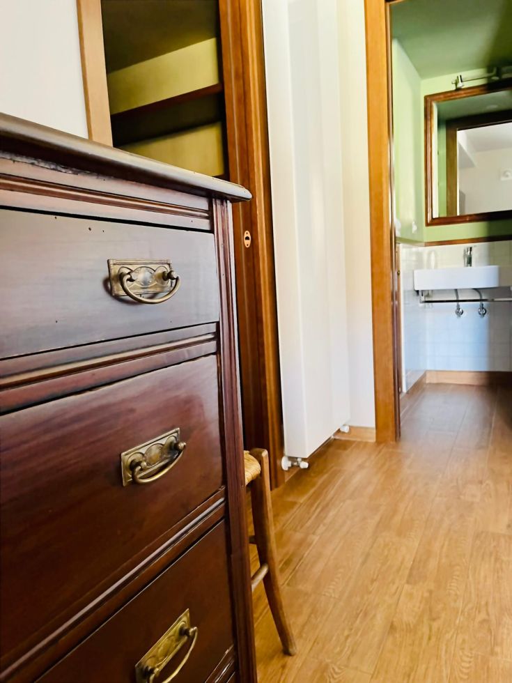 Interno di un ambiente con mobili in legno e panorama su una stanza attigua.